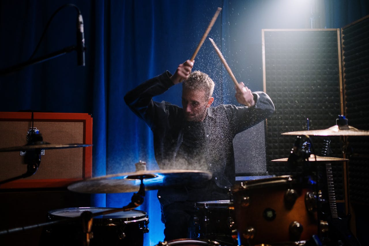 Energetic drummer playing in a music room with vibrant lighting and acoustic panels.